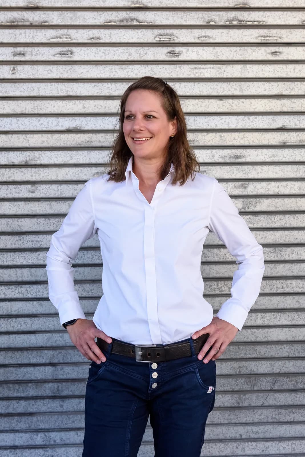 Leila Steiner stehend vor einer Wellblechwand.