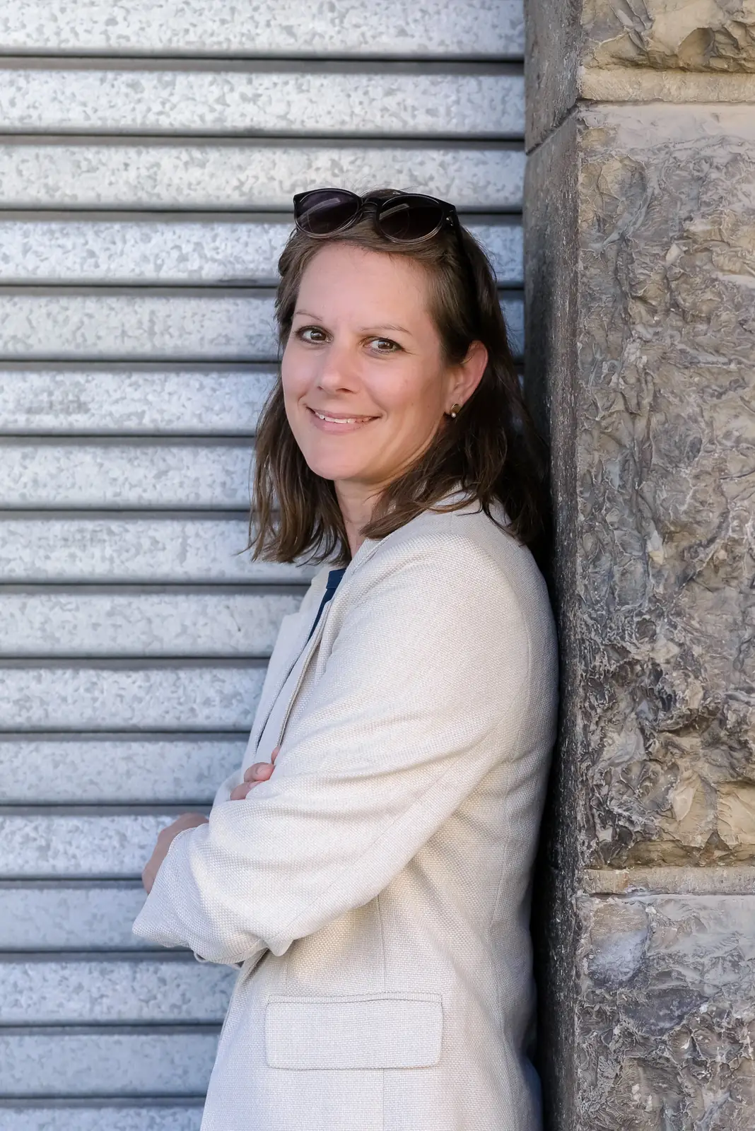 Leila Steiner, an eine Wand gelehnt, mit verschränkten Armen.