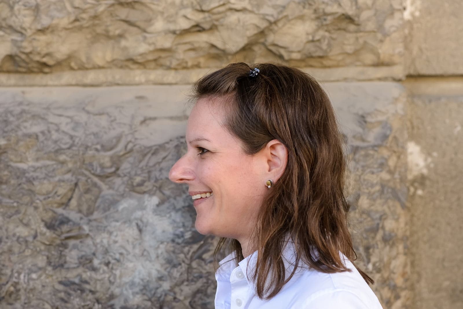 Leila Steiner im Profil vor einer Natursteinwand.